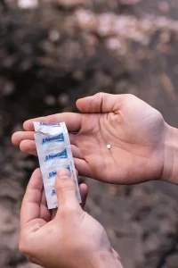 Person holding a single Aquatabs 67mg water purification tablet in their hand